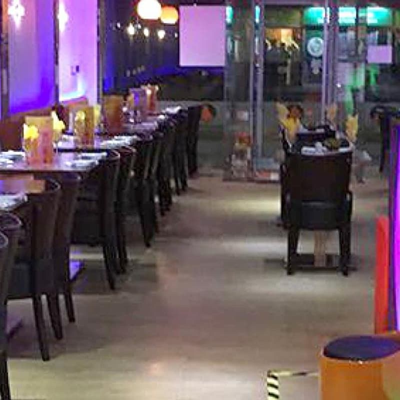 The dining room laid for service, banquette seating along the wall under violet lighting.