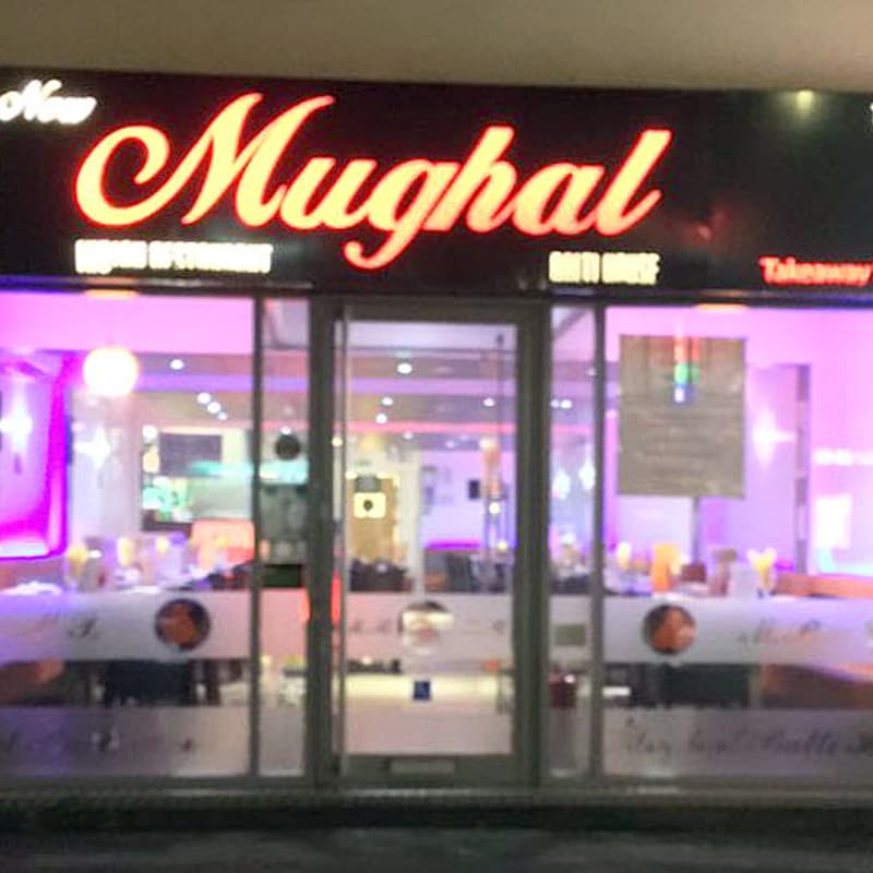 The Mughal Restaurant shopfront on Washway Road at night, its illuminated red sign above the window.